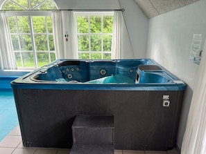 A hot tub in a room with a view of greenery through a window. - 5 Star Holiday Home in Ulfborg (Ulfborg)