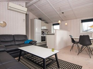A compact living space with a sofa, a dining table, and a kitchenette. - 5 Star Holiday Home in Juelsminde (Horsens)