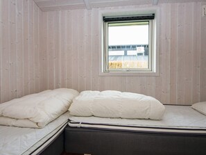 A room with a single bed, a window with a view of a building, and wooden walls. - 5 Star Holiday Home in Juelsminde (Horsens)