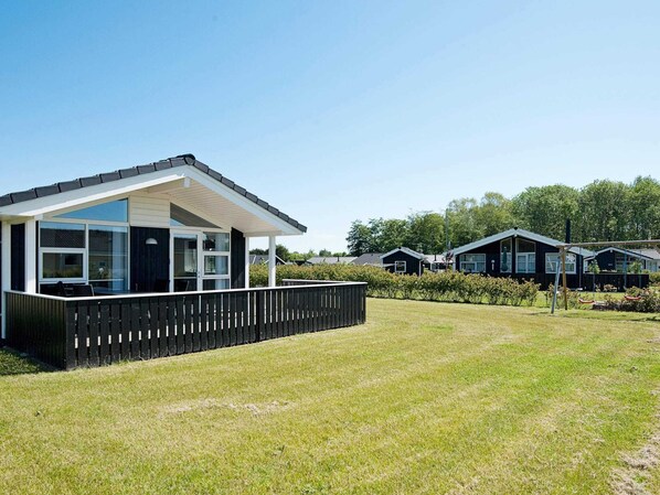 A modern vacation home with a large deck, a fenced yard, and a clear view of the surrounding area.