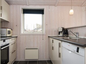 A compact kitchen with a window, a microwave, a coffee maker, and a dishwasher. - 5 Star Holiday Home in Juelsminde (Horsens)