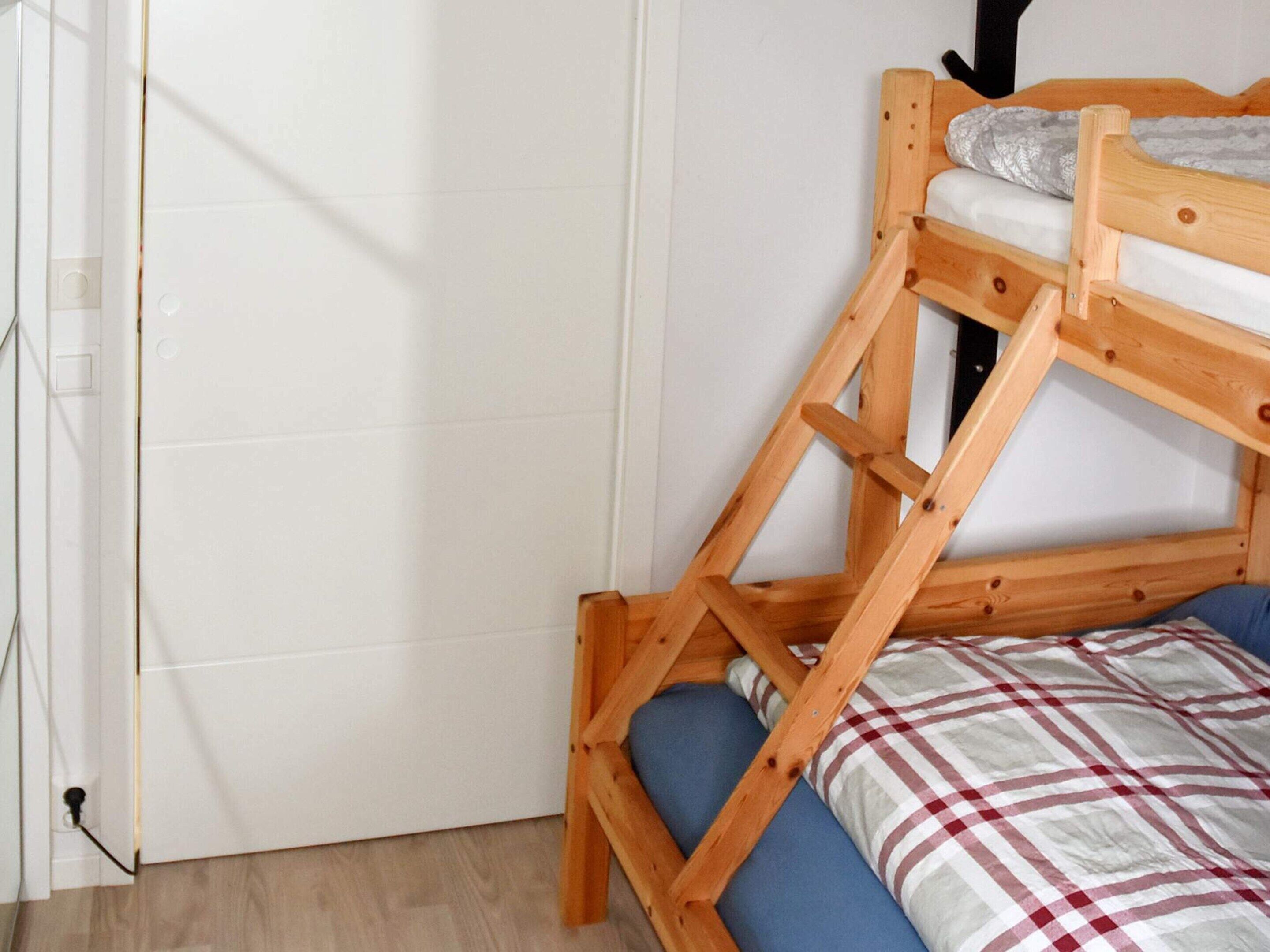 A bunk bed with a wooden frame and a blue mattress.