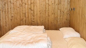 A room with a wooden panel wall, a bed with white bedding, and a door with a lock.