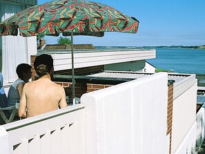 A balcony with a view of the water, a patterned umbrella, and a white fence. - 3 Person Holiday Home in Grasten (Grasten)