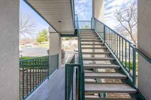 Stairs lead to an upper level with a view of the parking area and surrounding buildings.