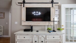 A white dresser with multiple drawers and a mounted television above it.