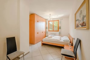 A bedroom with a bed, a chair, a wardrobe, and a painting on the wall. - 3 bedroom Italian Lakes apartment (Bedero)