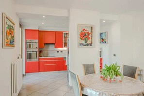 Une cuisine moderne avec des meubles de rangement rouges et un coin repas doté d’une table ronde.