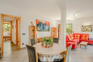 A modern living room with a round dining table, red sofa, and artwork on the walls.