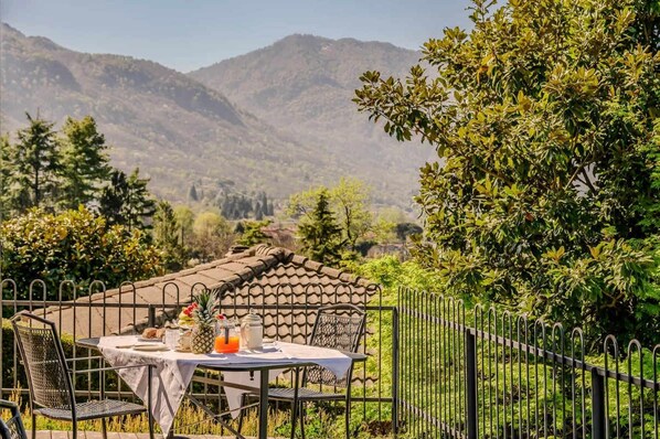 An outdoor dining area with a table set for two, overlooking a mountainous landscape. - 3 bedroom Italian Lakes apartment (Bedero)