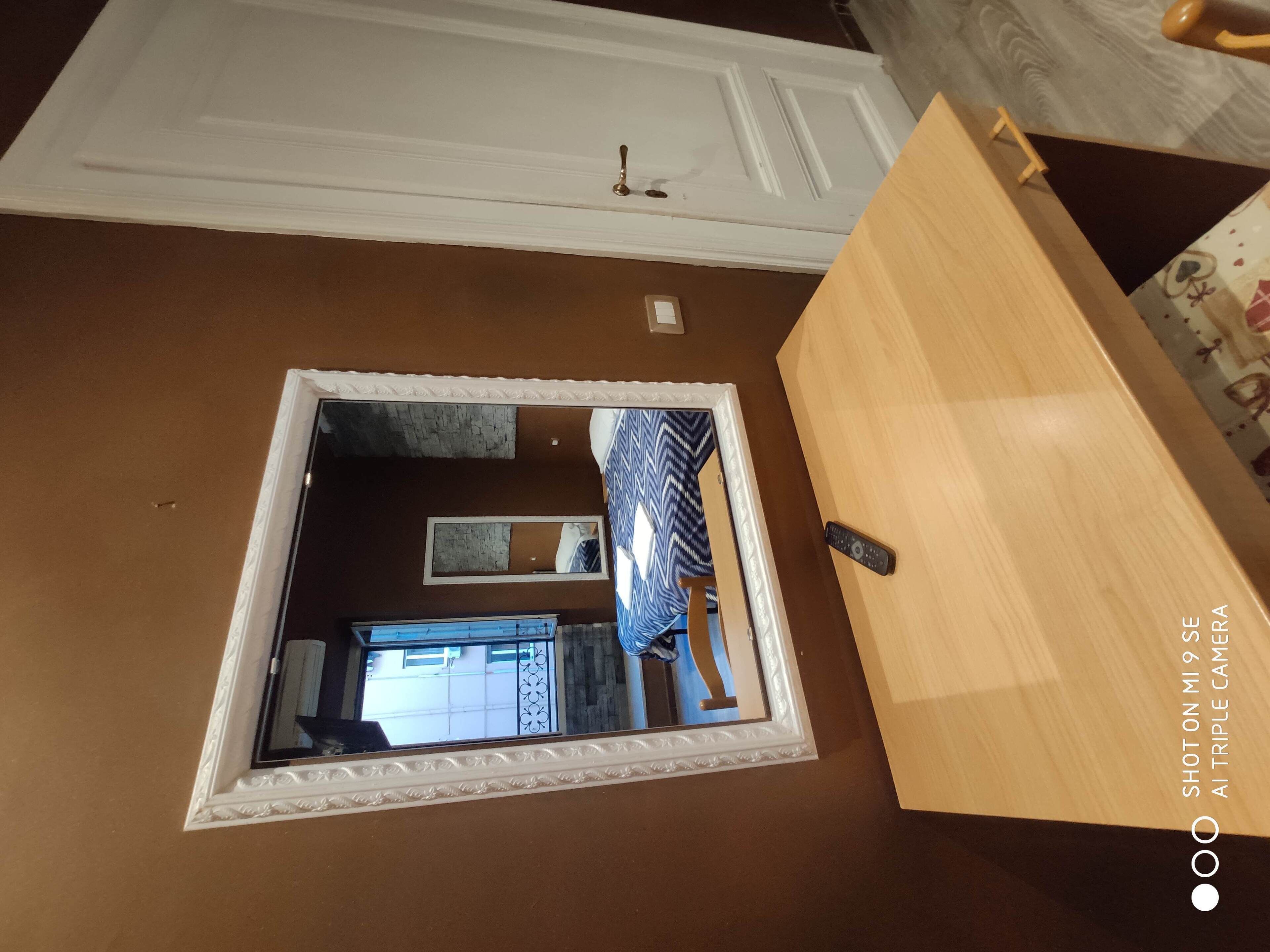 A room with a large mirror, a wooden door, and a small window.