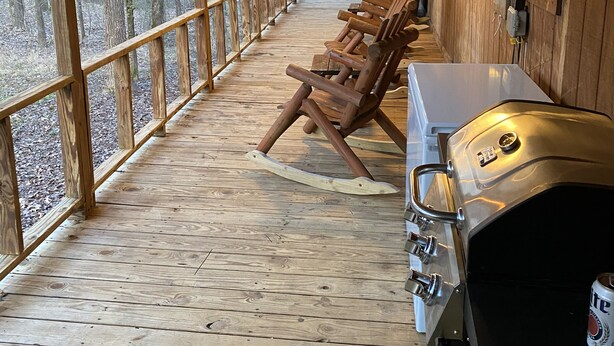Une terrasse extérieure couverte, dotée de bancs en bois et d’un barbecue.