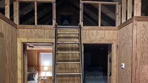 Un intérieur en bois avec un escalier central en bois menant à une mezzanine aménagée en espace nuit.