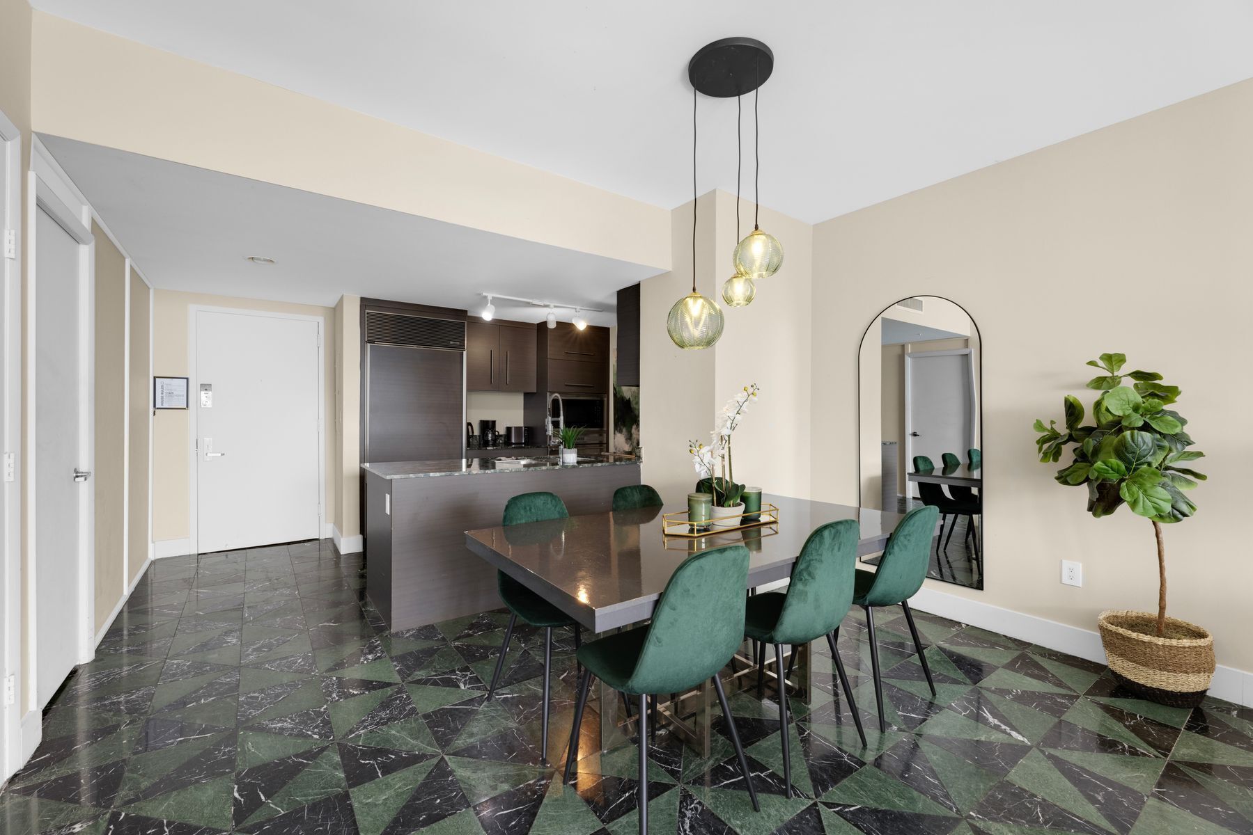 A modern kitchen with dark marble flooring, a central island, and green chairs.