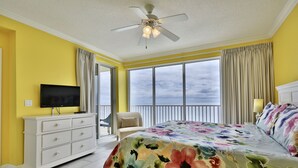 A bedroom with a bed, a TV, a dresser, and a balcony with curtains. - 14th Floor 3BR 2BA at the Boardwalk!! (Panama City)