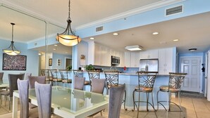 A modern kitchen with white cabinets, stainless steel appliances, and a glass dining table with chairs.