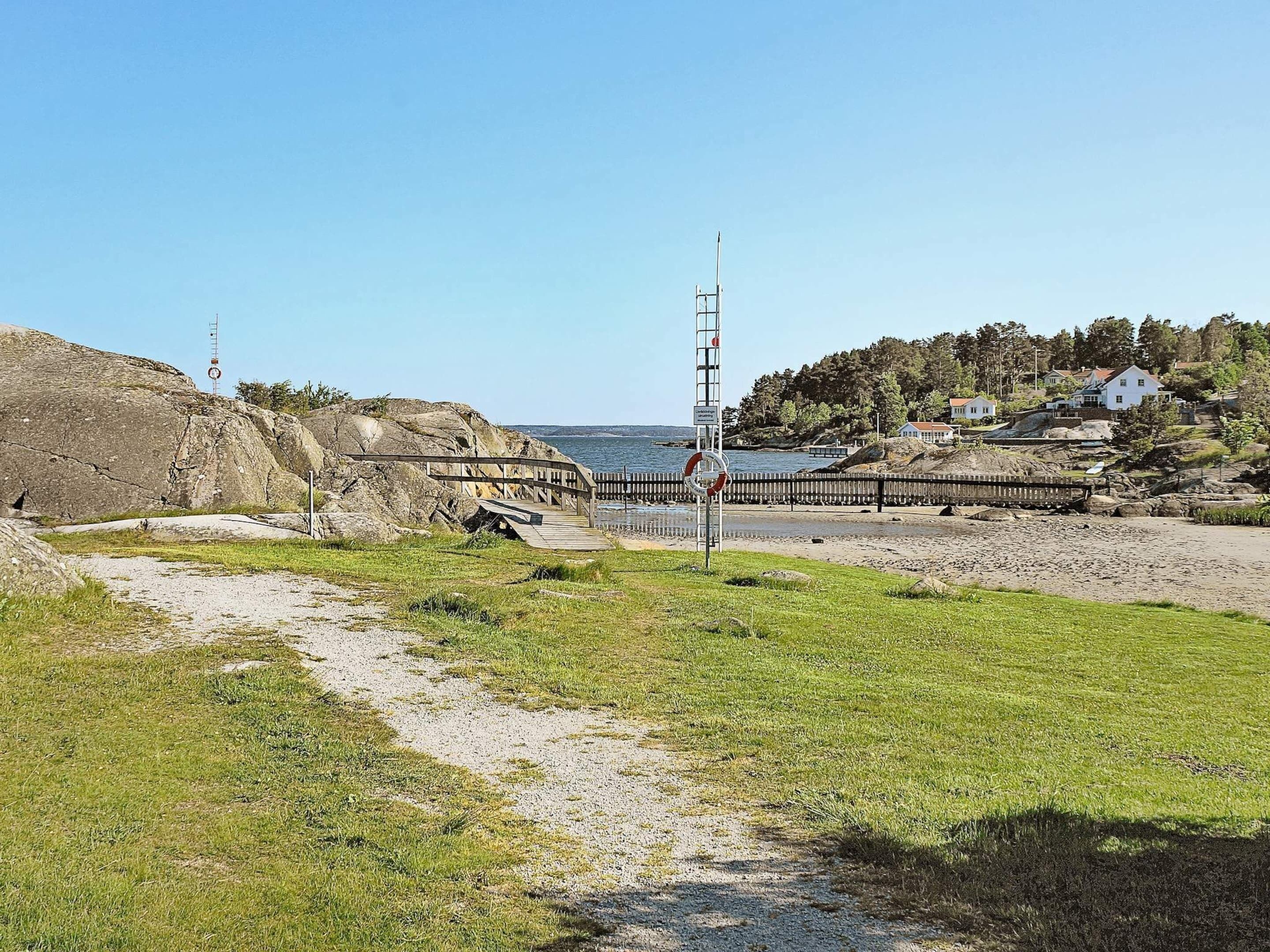 A coastal area with a wooden bridge, a lifebuoy, and a rocky shoreline.