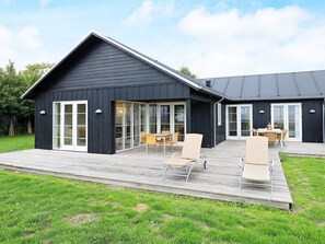A modern black building with large glass doors and a wooden deck with outdoor furniture. - 5 Star Holiday Home in Nysted (Nysted)