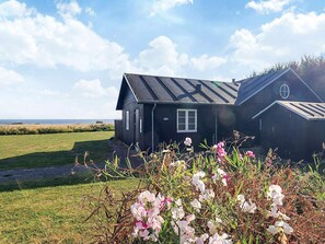 A black house with a sloped roof, a small window, and a door. - 5 Star Holiday Home in Nysted (Nysted)