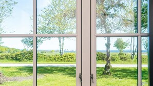 A window with a view of a grassy area, trees, and a road. - 8 Person Holiday Home in Knebel-by Traum (Knebel)