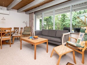 A living room with a sofa, chairs, a coffee table, and large windows offering a view of greenery. - 5 Person Holiday Home in Ebeltoft (Ebeltoft)