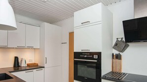 Una cocina moderna con armarios blancos, un horno negro y una encimera de acero inoxidable.