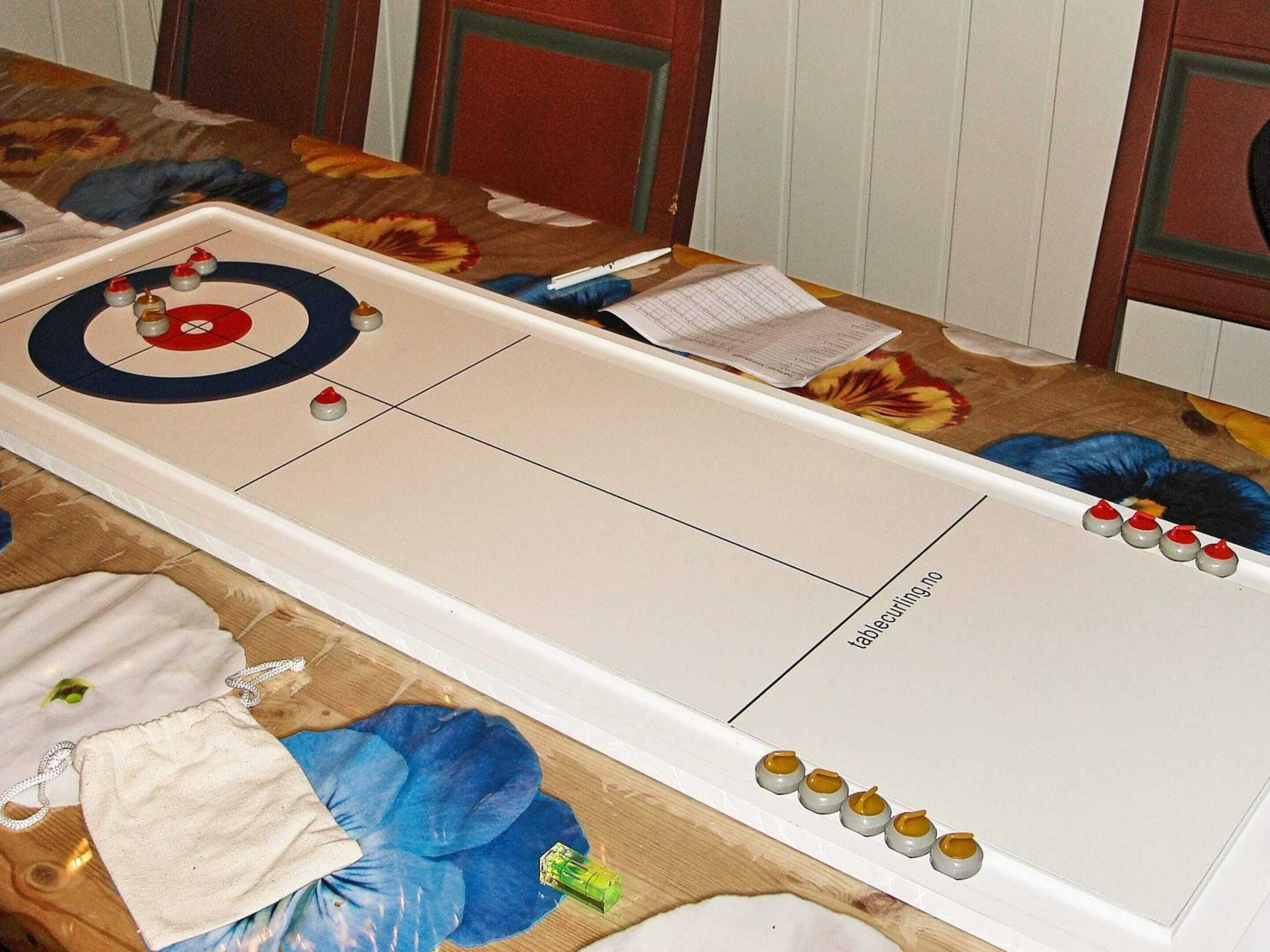 A shuffleboard table with a target, numbered pucks, and a paper score sheet.