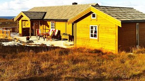 A yellow wooden building with a porch and outdoor seating area. - Holiday Home in Dyrvik (Frøya)