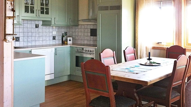 A kitchen with a dining table and chairs, a stove, and cabinets. - Holiday Home in Dyrvik (Frøya)