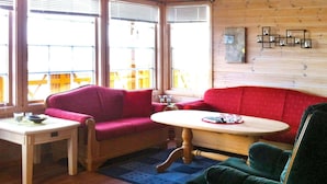 A room with a red sofa, a wooden table, and a green armchair. - Holiday Home in Dyrvik (Frøya)