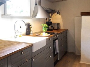 A kitchen with a wooden countertop, a sink, a stove, and a microwave.