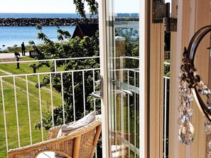 A balcony with a wicker chair, a view of the sea, and a metal railing. - Holiday Home in Sölvesborg (Sölvesborg)