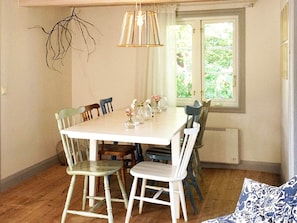 A dining area with a white table, chairs, and a hanging light fixture. - Holiday Home in Sölvesborg (Sölvesborg)