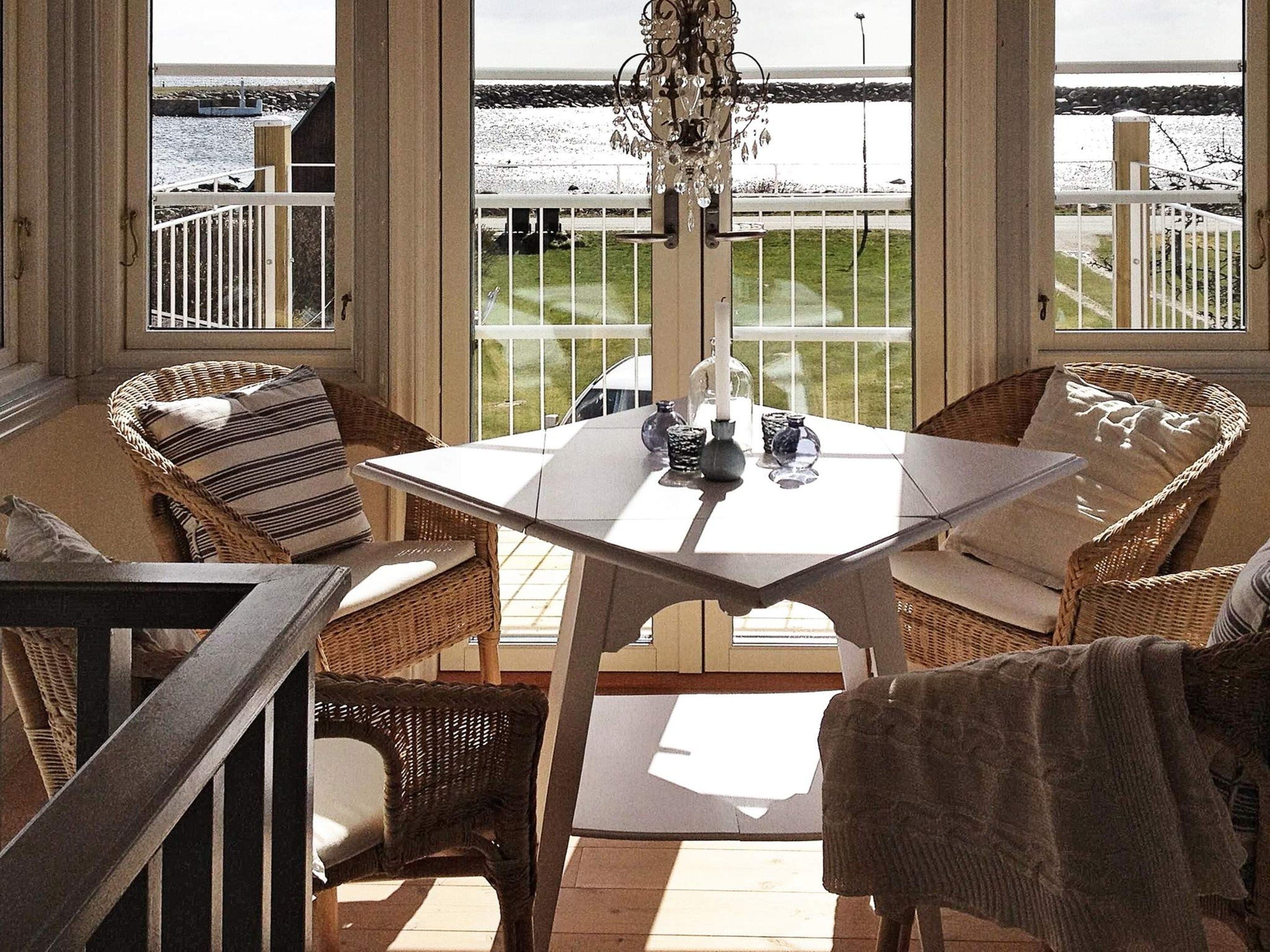 Una habitación soleada con muebles de mimbre, una mesa con adornos y vistas a una costa rocosa.