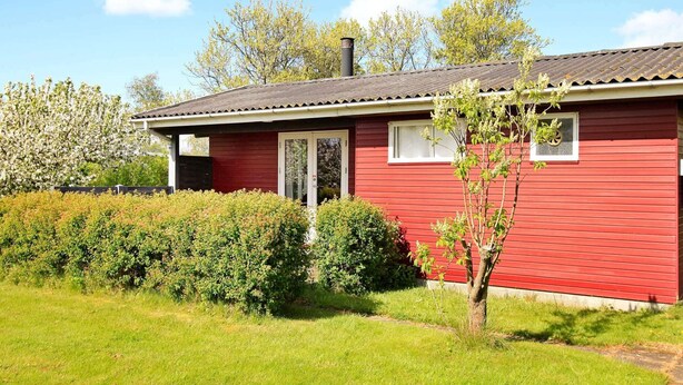 A red single-story house with a dark roof, white windows, and a small porch.