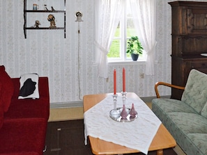 A cozy living room with a red sofa, a green armchair, a wooden table with candles, and a window with a plant. - 6 Person Holiday Home in Gullesfjord (Kvæfjord)