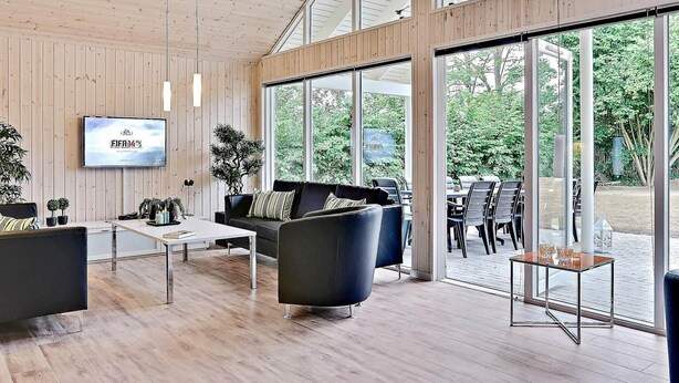 A modern interior with wooden panel walls, a mounted TV, and a view of the outdoors. - Pet Friendly Holiday Home in Dronningmølle near Sea (Dronningmolle)