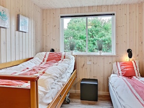 A room with two beds, a window, and wooden walls.