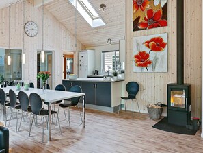 A spacious dining area with a long table and chairs, a kitchen with a modern design, and a fireplace. - Pet Friendly Holiday Home in Dronningmølle near Sea (Dronningmolle)