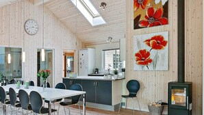 A modern kitchen with a central island, wooden walls, and a dining area with a table and chairs. - Pet Friendly Holiday Home in Dronningmølle near Sea (Dronningmolle)