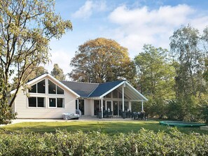 A two-story house with a covered patio and a lawn. - Pet Friendly Holiday Home in Dronningmølle near Sea (Dronningmolle)