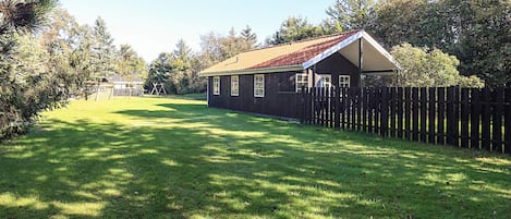 A wooden house with a fenced yard and a swing set.