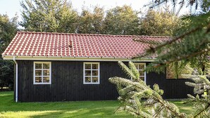 A single-story building with a dark wooden exterior and a red-tiled roof. - Stylish Holiday Home in Hals near Sea (Hals)