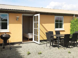 A patio with a table and chairs, a grill, and a sliding door leading to a room. - 6 Person Holiday Home in Faaborg (Faaborg)