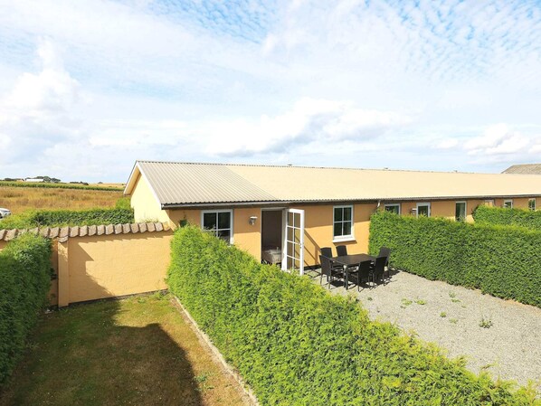 A single-story building with a flat roof, a covered patio area with a table and chairs, and a well-maintained lawn. - 6 Person Holiday Home in Faaborg (Faaborg)