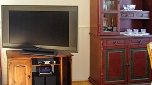 A television on a wooden stand, a cabinet with glass doors, and a patterned rug. - 8 Person Holiday Home in Afarnes (Rauma)