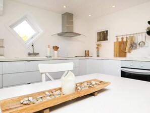 A modern kitchen with white cabinetry, a built-in oven, and a window above the sink. - Rustic Holiday Home in Skagen near Sea (Skagen)