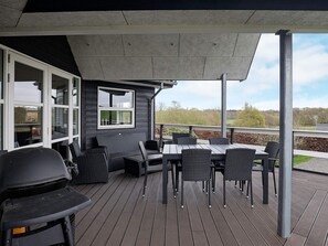 A covered outdoor patio with a table and chairs, a grill, and a view of the surrounding landscape. - 4 Star Holiday Home in Roslev (Roslev)