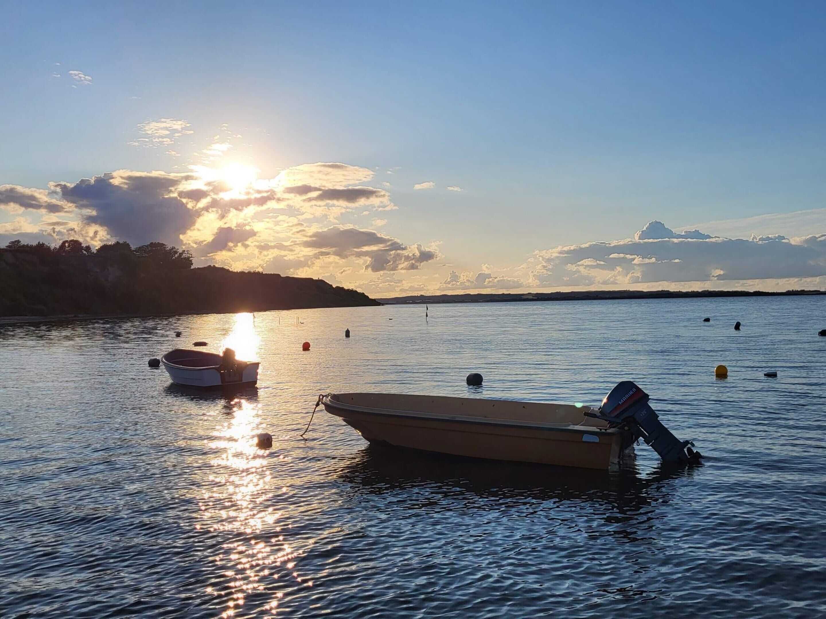 Een rustig meer bij zonsondergang, met boten en boeien.