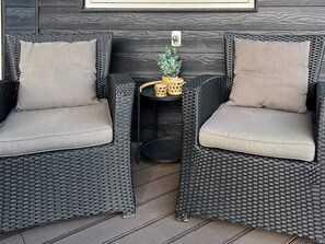 Two wicker chairs with cushions, a small table with a plant, and a wall-mounted light switch. - 4 Star Holiday Home in Roslev (Roslev)